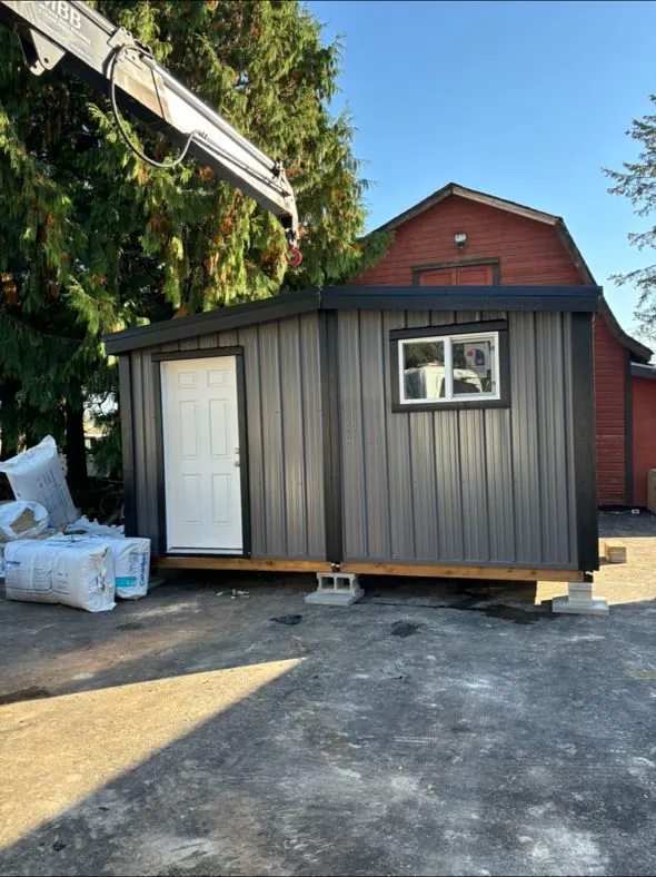 Dark grey shed beside a red barn