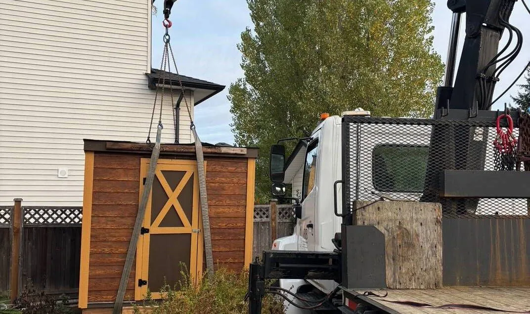 Crane lifting a cedar-look shed