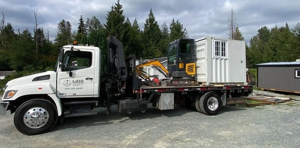 Flatbed crane truck carrying an excavator